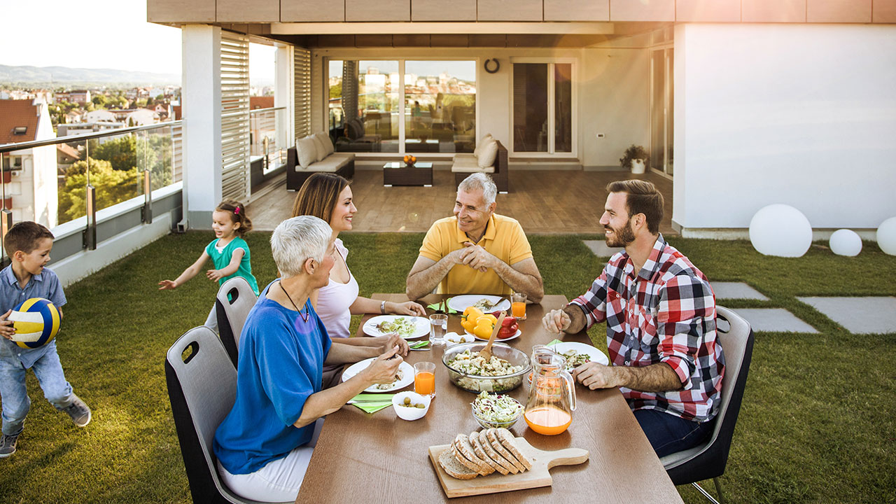 multigenerational family eating dinner at backyard table